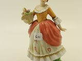 a figurine of a woman holding a basket of flowers