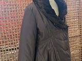 the jacket is on a mannequin stand in front of a woven wall