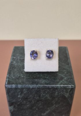 a pair of tanzanite earrings sitting on top of a marble block