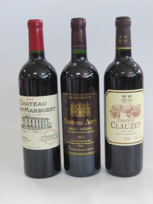 three bottles of wine are lined up on a white surface