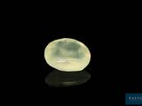 une pierre de jade jaune posée sur une surface noire, avec un reflet