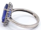 silver ring with a blue stone surrounded by diamonds on a white surface