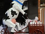 une statue représentant une vache à vélo tirant une charrette remplie de peinture