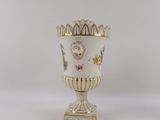 a white vase that has a gold decoration on it