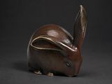 une figurine de lapin marron posée sur une surface noire