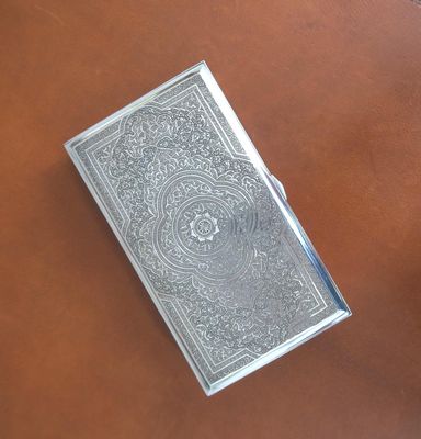 a silver book sitting on top of a leather table next to a cup of coffee