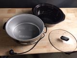une casserole avec un couvercle posée sur une table, à côté d'une autre casserole avec un couvercle
