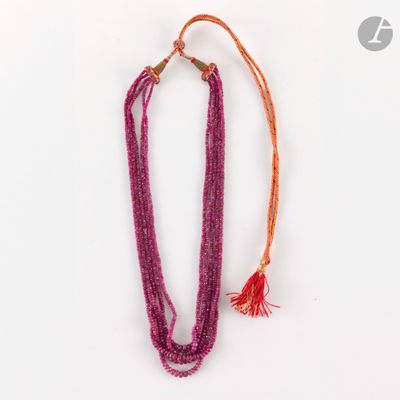 un gros plan d'un collier posé sur une surface blanche, avec un cordon rouge