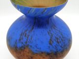 a blue vase with a gold rim sitting on a white surface