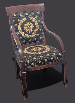 une chaise ancienne en bois dont l'assise est recouverte d'un tissu à motifs noirs et dorés