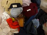 a pile of clothes on a bed with a hat on top of it