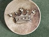 une pièce d'argent sur laquelle figure une couronne, posée sur un fond vert