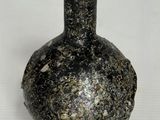 un vase noir posé sur une surface blanche