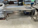 tables de travail et éviers en acier inoxydable dans un entrepôt, avec des palettes en arrière-plan