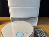 une image représentant un robot aspirateur blanc posé sur une table en bois