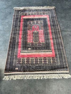 un tapis noir et rose avec une bordure rouge posé au sol