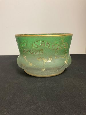 a green vase sitting on a table with a white wall in the background