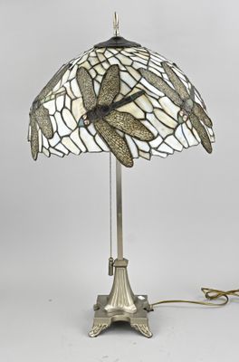 une lampe posée sur une table, dont l'abat-jour représente une libellule