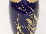 a blue vase with gold decoration on it on a white surface