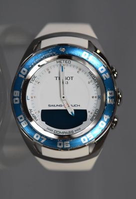 a close up of a wrist watch with a white and blue band