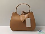 the brown handbag is sitting on the table with a tag on it