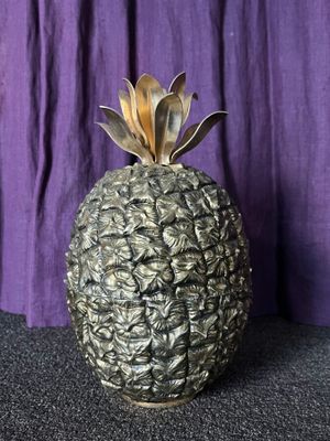 a small pineapple sitting on a table with a purple curtain in the background
