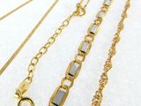 three different types of gold chains on a white surface