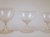 three glass goblets sitting on top of a white surface