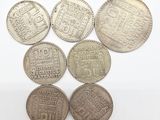 six pièces d'argent de formes et de tailles différentes sur un fond blanc