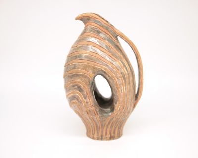 a brown vase with a curved handle on a white surface