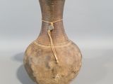 un vase marron entouré d'une corde, posé sur une table