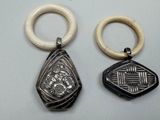 two pieces of silver and ivory jewelry on a white surface