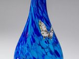 a blue vase with butterflies on it on a white surface