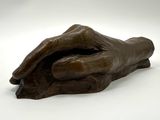 statue représentant une main tenant un morceau de bois sur une surface blanche