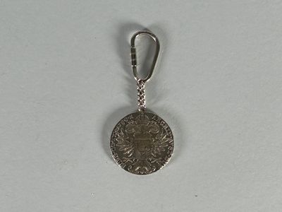 an image of a silver coin with a keychain on a white surface