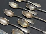 six silver spoons are lined up on a black surface