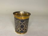 une tasse dorée et noire ornée d'un motif représentant des oiseaux