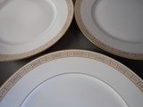 three white plates with gold trim on them on a table