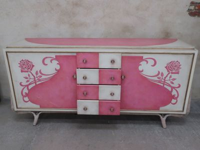 a pink and white dresser with drawers and drawers on it