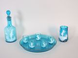 une assiette bleue sur laquelle sont posés une bouteille et un verre