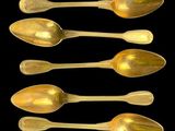 six gold spoons are lined up in a row on a black background