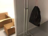 a black bag hanging on a metal rack in the corner of a room