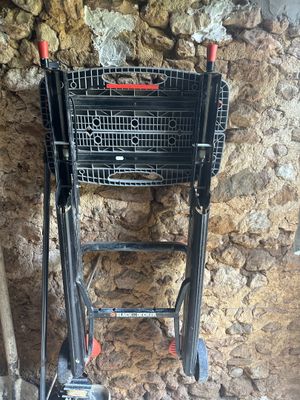 un caddie noir posé à côté d'un mur en pierre