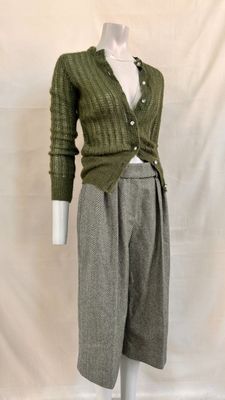 a mannequin wearing a green sweater and grey pants