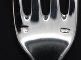 a silver fork with holes in it on a black surface