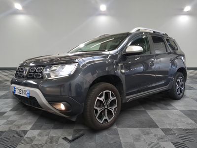 La Dacia grise est garée dans une grande pièce au sol carrelé en damier.