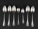 six silver spoons are lined up in a row on a black surface