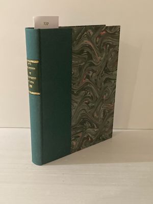 un livre vert posé sur une table en bois, près d'un mur blanc