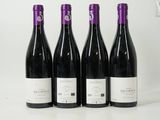 quatre bouteilles de vin sont alignées sur une surface blanche