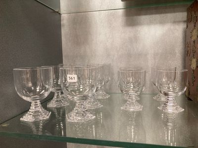 Plusieurs verres à vin vides sont posés sur une étagère en verre dans une pièce.